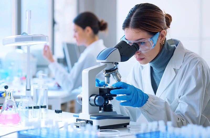 A female researcher in a laboratory looking in a microscope.